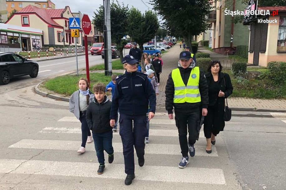 dzieci przechodzą przez przejście dla pieszych, obok policjanci i uczniowie z klasy mundurowej