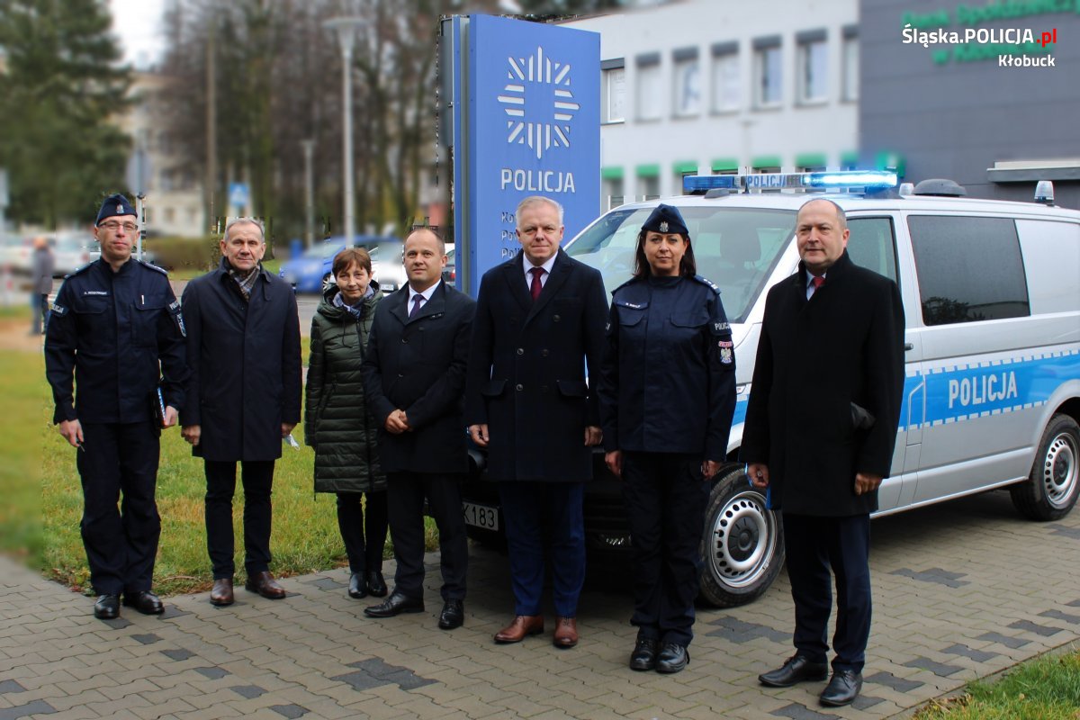 samorządowcy oraz policjanci stoją przed budynkiem Komendy Policji w Kłobucku, obok nowy oznakowany radiowóz