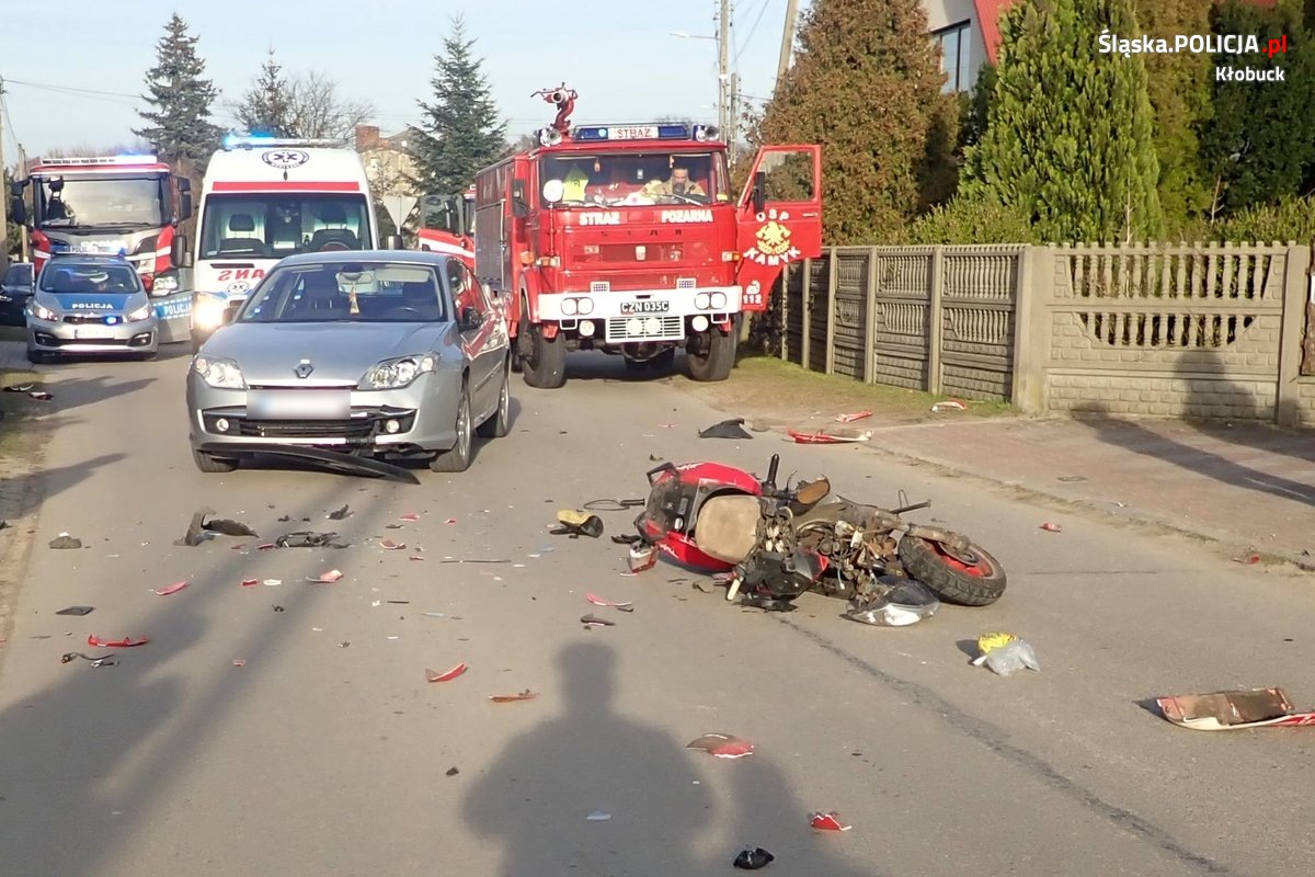 Zdjęcie przedstawia miejsce zdarzenia drogowego z udziałem skutera i osobowego renault oraz pojazdy służb ratowniczych.