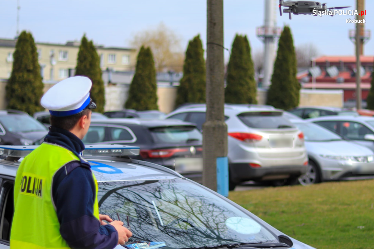 Zdjęcie przedstawia umundurowanego policjanta ruchu drogowego, który steruje dronem.