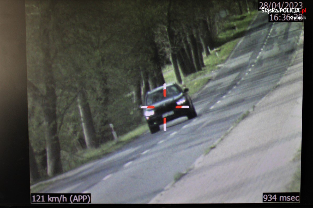 zdjęcie monitora, na którym widać ciemny samochód jadący ulicą