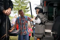 Dzieci przymierzają policyjną kamizelkę przeciwuderzeniową.