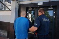 Policjant prowadzi zatrzymanego.