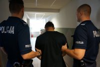 Policjanci prowadzą zatrzymanego.