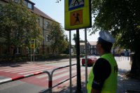 Policjant sprawdza oznakowanie przejścia dla pieszych przy szkole.