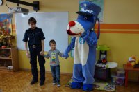 Sznupek i policjantka uczą dzieci przechodzenia przez pasy.