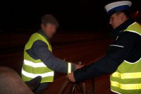 Policjant wręcza pieszemu odblaski.
