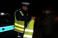 Policjant wręcza pieszym odblaski.