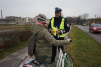 Policjant wręcza kamizelkę odblaskową.