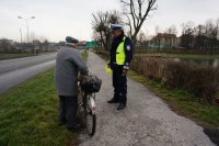 Policjant wręcza kamizelkę odblaskową.