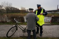 Policjant wręcza kamizelkę odblaskową.