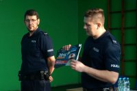 Policjant wręcza dzieciom kalendarz ze Sznupkiem.