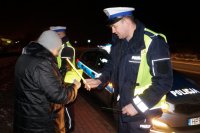 Policjanci wręczają pieszej odblaski.