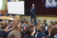 Uczniowie Szkoły Podstawowej nr 1 w Kłobucku słuchają pogadanki policjanta.