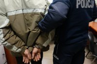 Policjant prowadzi zatrzymanego.