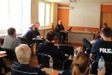 Zdjęcie kolorowe. Sala konferencyjna, kilkunastu policjantów słucha prelekcji powiatowego lekarza weterynarii.