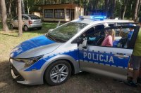 dzieci stoją przy radiowozie