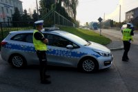 policjanci prowadzą stoją przy radiowozie i prowadzą działania prędkość, mierzą prędkość i kontrolują auta