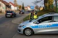 policjanci prowadzą stoją przy radiowozie i prowadzą działania prędkość, mierzą prędkość i kontrolują auta