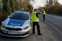 policjanci prowadzą stoją przy radiowozie i prowadzą działania prędkość, mierzą prędkość i kontrolują auta