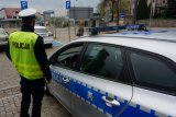 policjant stoi przy radiowozie na kłobuckim rynku i obserwuje przejście dla pieszych