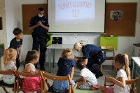policjantka pokazuje dzieciom jak chronić się przed atakującym nas psem