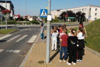 policjanci znajdujący się przed przejściem dla pieszych tłumaczą najmłodszym uczniom zasady bezpiecznego przechodzenia przez jezdnię