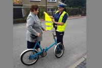 policjantka wręcza rowerzyście kamizelkę odblaskową