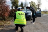 policjant wraz z kierująca zatrzymanym do kontroli pojazdem sprawdzają stan techniczny świateł