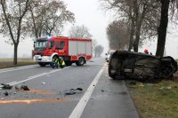 fotografia przedstawia policjantów wykonujących oględziny na tle wozu strażackiego oraz rozbitego forda