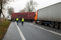fotografia przedstawia policjanta na tle rozbitego volvo oraz innego pojazdu ciężarowego, który nie brał udziału w zdarzeniu