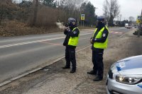 policjanci ruchu drogowego, jeden z nich mierzy prędkość nadjeżdżającego samochodu
