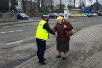 policjantka ruchu drogowego zakłada opaskę odblaskową seniorce