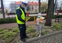 policjant ruchu drogowego rozdaje odblaski małej dziewczynce
