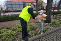 policjant ruchu drogowego zakłada opaskę odblaskowa dziewczynce