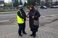 policjantka ruchu drogowego zakłada opaskę odblaskowa pieszej