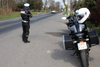 policjant ruchu drogowego mierzący prędkość, z prawej strony motocykl policyjny