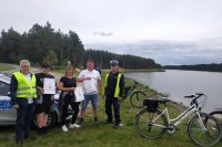 policjant ruchu drogowego, pracownik urzędu gminy i i rowerzyści trzymający odblaski