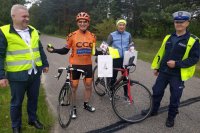 policjant ruchu drogowego, pracownik urzędu gminy i rowerzyści trzymający odblaski