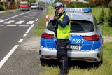policjant stoi przy radiowozie i kontroluje prędkość