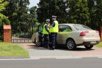 trzech policjantów stoi przy kontrolowanym samochodzie