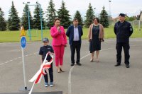 Kobieta z mikrofonem przemawia, na pierwszym planie stoją dzieci przebrane za policjantów