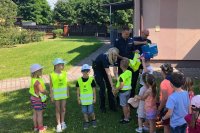 policjanci rozdają kamizelki odblaskowe, część dzieci już jest ubrana w kamizelki odblaskowe.