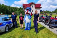 umundurowani policjanci stoją przodem do zdjęcia wraz z policyjną maskotką i nastoletnim chłopakiem