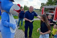 policjant rozdaje odblaski dzieciom, obok stoi policyjna maskotka