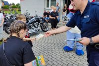 policjant rozdaje dzieciom profilaktyczne broszurki