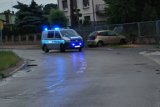 oznakowany radiowóz stoi na ulicy z włączonymi światłami błyskowymi prze samochodzie, który uderzył w płot