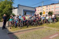 policjantka i policjant w mundurze stoją obok dzieci z rowerami