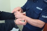 umundurowany policjant zakłada kajdanki zatrzymanemu