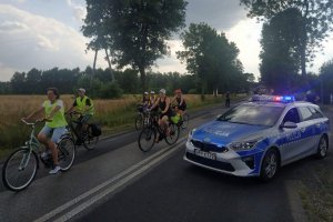 radiowóz policyjny w tle jadący rowerzyści